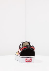 Schwarze Wildledersneaker mit orangefarbigen, gelben und weißen Akzenten, ausgestattet mit einer weißen Sohle und rotem "Vans Off The Wall"-Logo an der Ferse.