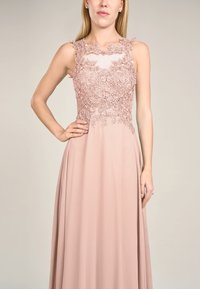 Abito da sera rosa blush con corpetto in pizzo floreale, design senza maniche, bordi ondulati e gonna fluida. Tessuto morbido con una texture liscia.