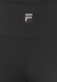 Czarne legginsy o gładkiej fakturze, z wysokim stanem i jasnoróżowym logo z przodu. Szwy wykończeniowe wzdłuż talii.