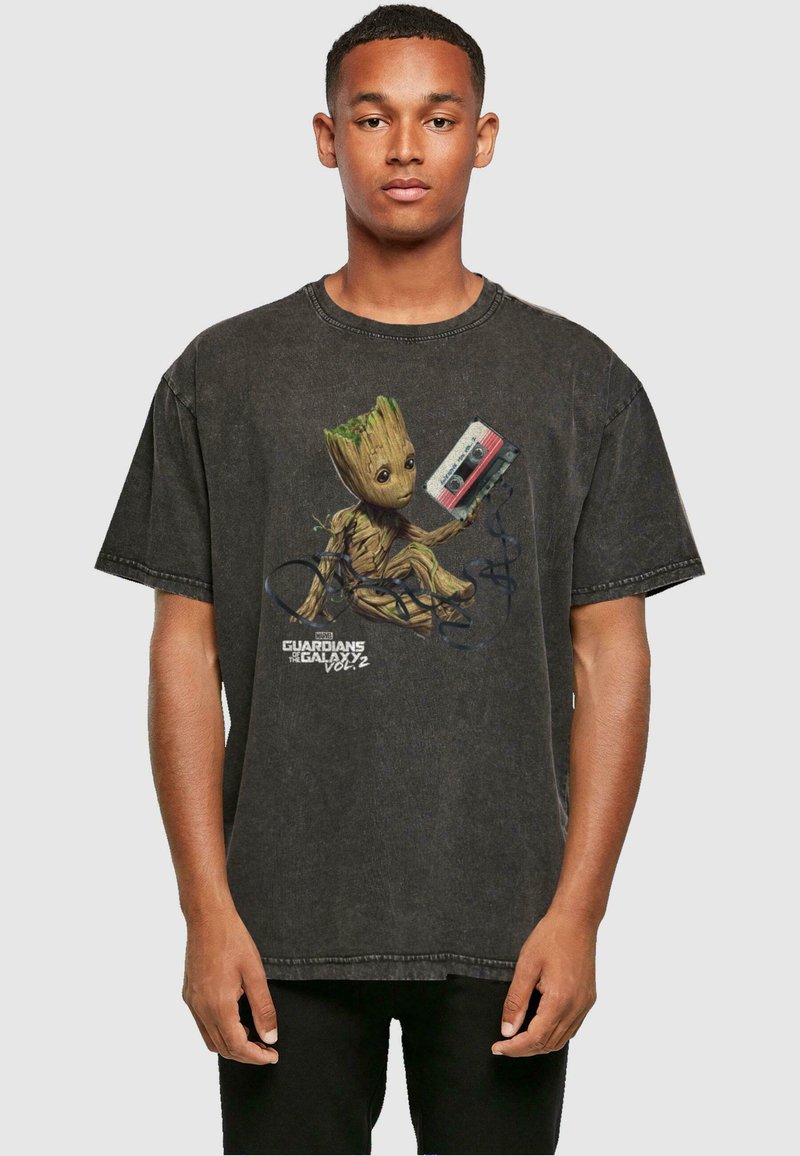 Camiseta negra de gran tamaño hecha de algodón, con un diseño impreso de Groot sosteniendo una cinta de casete, con el texto "Guardianes de la Galaxia Vol. 2".