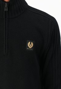 Sweater preto canelado com gola de meio zíper e um pequeno patch do logótipo da Belstaff em bege e preto no peito.