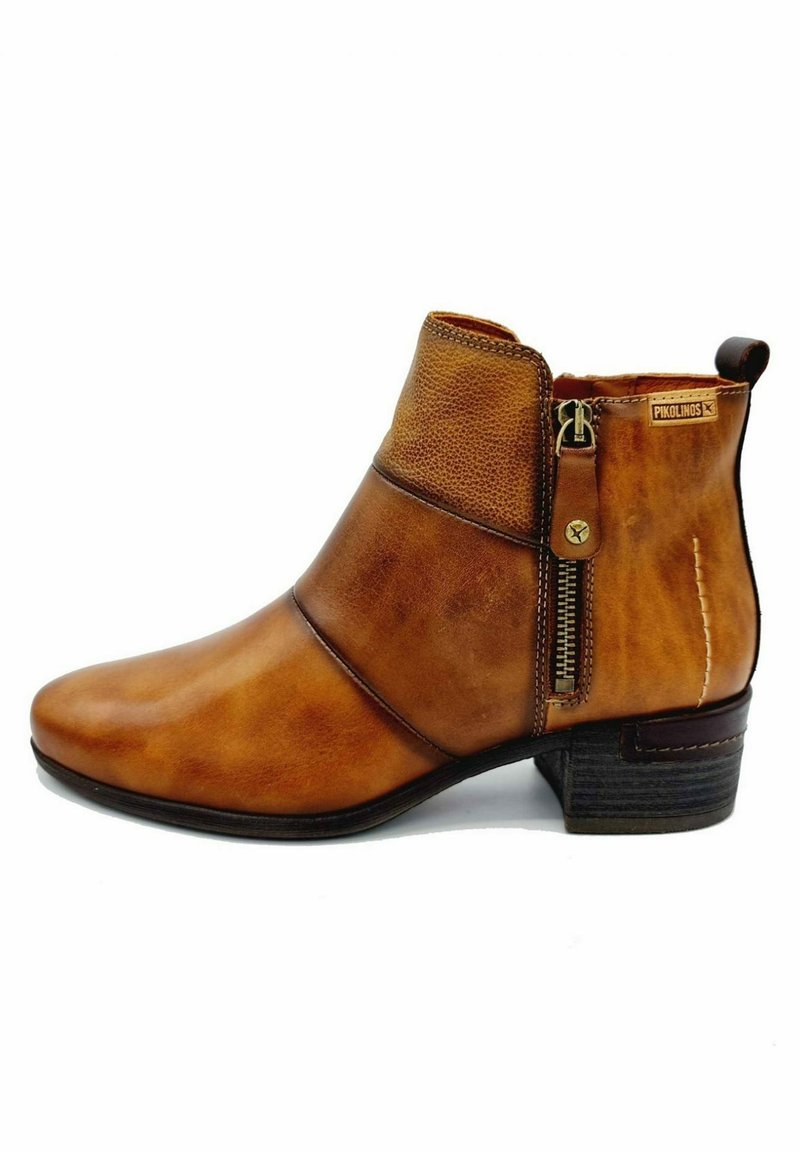 Bottine en cuir marron avec fermeture éclair latérale, talon bas empilé, bord supérieur texturé et étiquette de marque près du haut à l’arrière.