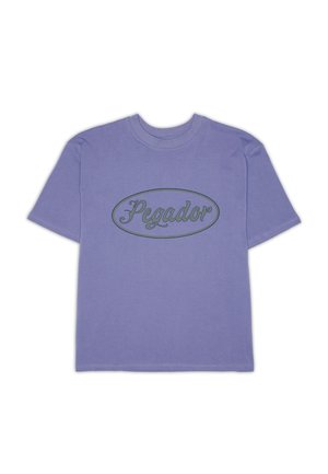 Fioletowa koszulka z krótkim rękawem i okrągłym dekoltem, z napisem "Pegador" w skrypcie wewnątrz ciemnego owalu na klatce piersiowej.