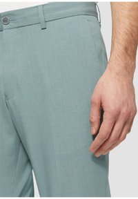 Light blue tailored pants made of smooth fabric, featuring a flat front, belt loops, and a side pocket, with a close-up of the waistband.
