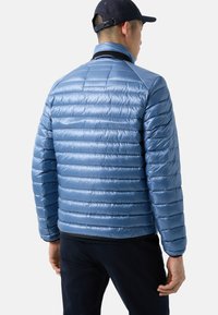 Light blue puffer jacket with horizontal quilted pattern, high collar, smooth finish, and elastic cuffs. Features a fitted silhouette.