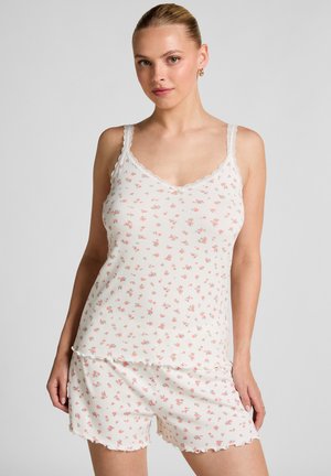 White floral-patterned tank top with scalloped lace straps and matching shorts. Made of lightweight, textured fabric, featuring small pink roses.