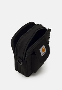 Svart stoffoppbevaringsbag med doble glidelåskompartments, rektangulær form, med et hvitt og oransje merke på forsiden.