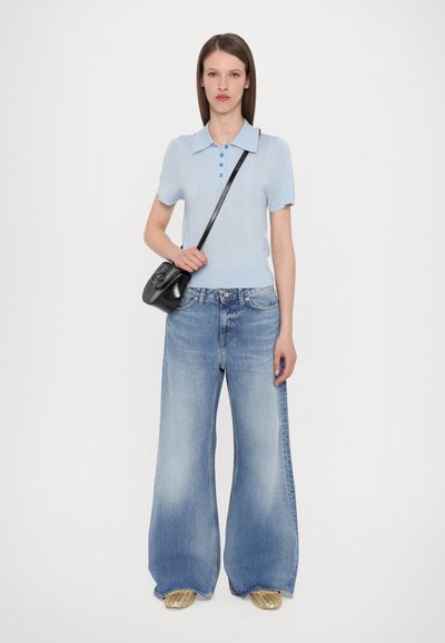 Világoskék, rövid ujjú pólóing gombos részletekkel, széles lábú, világoskék farmernadrággal párosítva. Fekete crossbody táska és arany cipők.