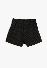 Shorts noirs à rayures verticales avec une taille élastique. Fabriqués en tissu doux, avec des rayures blanches verticales et une coupe décontractée.