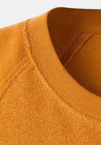 Close-up of a mustard yellow textured sweatshirt collar with detailed stitching and ribbed knit fabric.