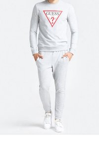 Grå bomulds sweatshirt med et rødt trekantet logo og matchende grå joggers. Båret med hvide sneakers, har en slim fit og ribbede mansjetter.