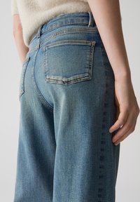 Jeans in denim lavaggio chiaro con vestibilità comoda, dotati di tasche posteriori e dettagli di cucitura discreti. Texture morbida e design classico a cinque tasche.