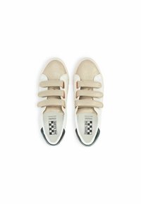 Beige en witte sneakers met drie klittenbandsluitingen, ronde neus, gestructureerd oppervlak en een zwarte hielaccent. Logo op de binnenzool.