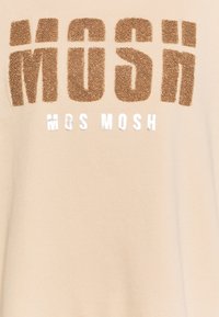 Sudadera beige con el destacado texto esponjoso en marrón y blanco "MOS MOSH." Textura suave con un ajuste relajado y sin estructura.