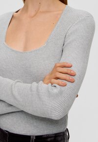 Hellgraues, geripptes Langarmshirt mit weitem Rundhalsausschnitt. Der Stoff wirkt weich und enganliegend, mit einer strukturierten Oberfläche und subtiler Dehnbarkeit.