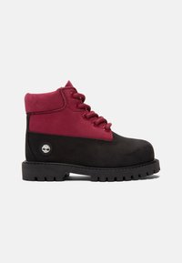 Botas de tobillo negras y burdeos con una parte superior de cuero texturizado, puntera redonda, cordones en la parte delantera y una suela de goma con un diseño de dibujo resistente.