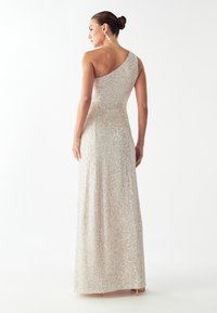 Vestido largo de un solo hombro en dorado brillante con una silueta ajustada y lentejuelas texturizadas, que presenta un diseño de espalda elegante y un brillo sutil.