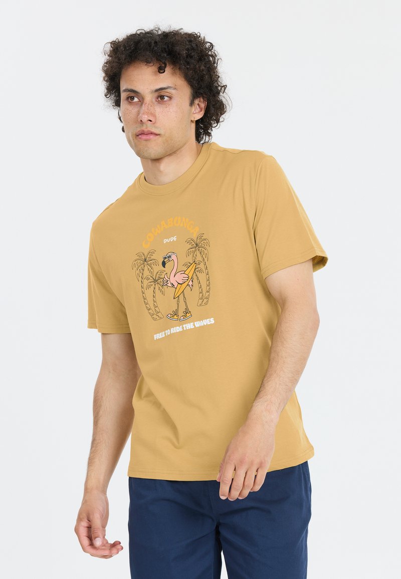 Senapsgul bomulls-t-shirt med en grafik av en flamingo med en surfbräda, omgiven av palmer och text. Kortsleeve, avslappnad passform.