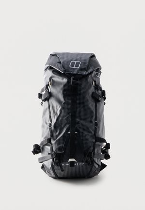 Mochila de senderismo enrollable en negro y gris con patrón de cuadrícula, múltiples correas, hebillas y un bolsillo delantero con cremallera, de pie sobre fondo blanco.