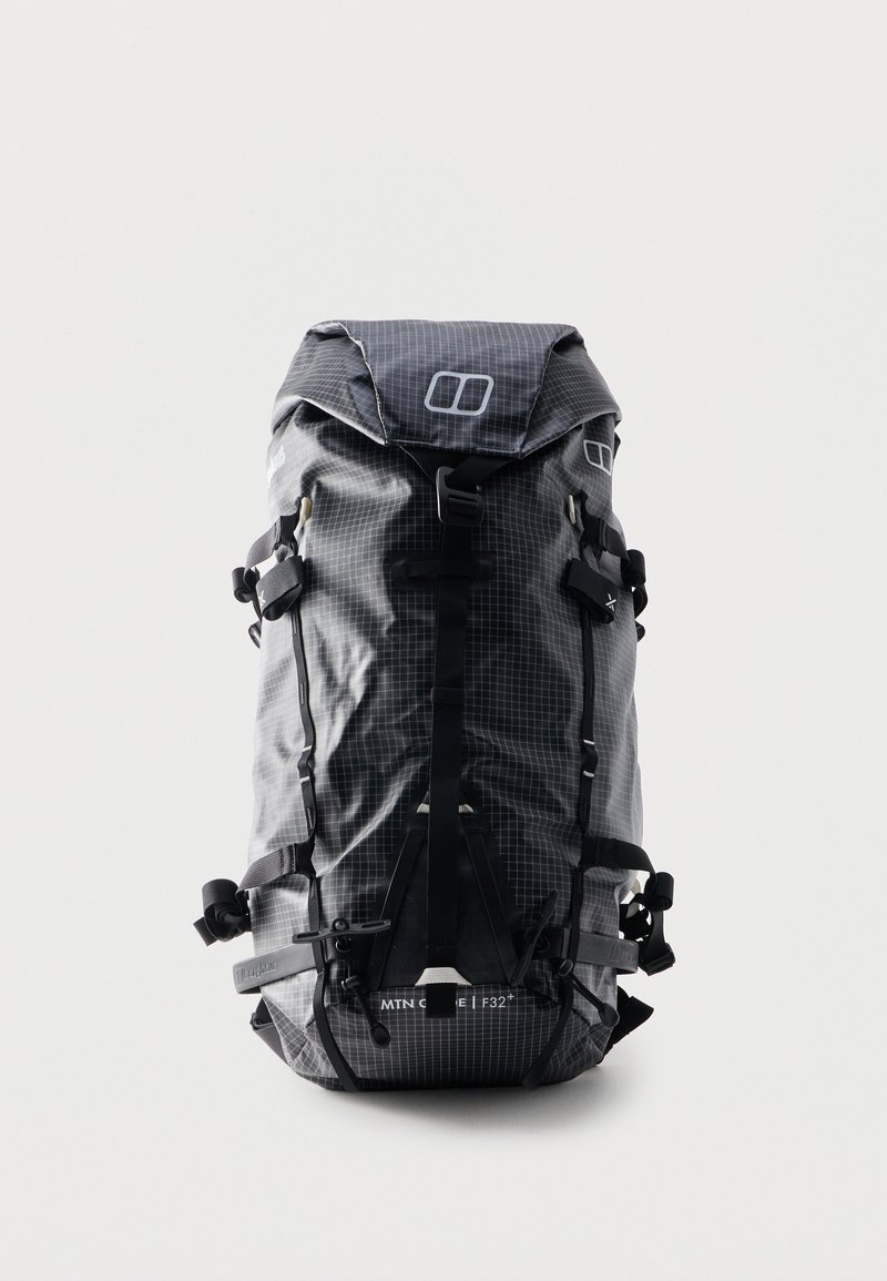 Μαύρο και γκρι σακίδιο πεζοπορίας με ρολό-επάνω και σχέδιο με πλέγμα, πολλαπλούς ιμάντες, αγκράφες και μπροστινή τσέπη με φερμουάρ, σε όρθια θέση σε λευκό φόντο.