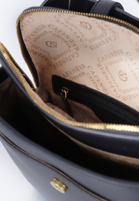 Sac à main noir avec un extérieur texturé, fermeture éclair dorée et doublure beige de marque. Il possède une poche zippée et des compartiments intérieurs divisés.