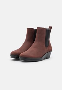 Bottines en suede marron au design épuré, dotées de panneaux latéraux élastiques et d'une semelle en caoutchouc noir, offrant un ajustement léger et confortable.