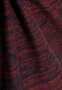 Tessuto lavorato a maglia con un motivo testurizzato in un rosso profondo e blu navy. La trama presenta una sottile variazione nei colori e nella densità.