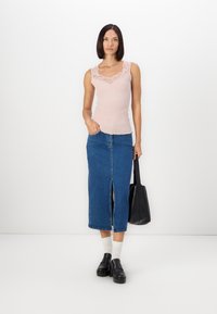 Light pink ribbed tank top with lace neckline, paired with a blue denim midi skirt featuring a front slit, black bag, and platform shoes.