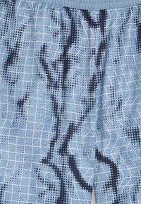 Calções de banho azul claro com um padrão de grelha, apresentando linhas onduladas e pontos azul escuro, cintura elástica e material leve.