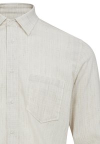 Camicia button-up beige chiaro con un motivo testurizzato, colletto a punta e una tasca sul petto. Realizzata in tessuto intrecciato.