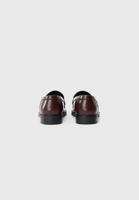 Brune lærloafers med et slankt design, glat tekstur og en sort gummisål. Subtile syninger forbedrer det samlede udseende.