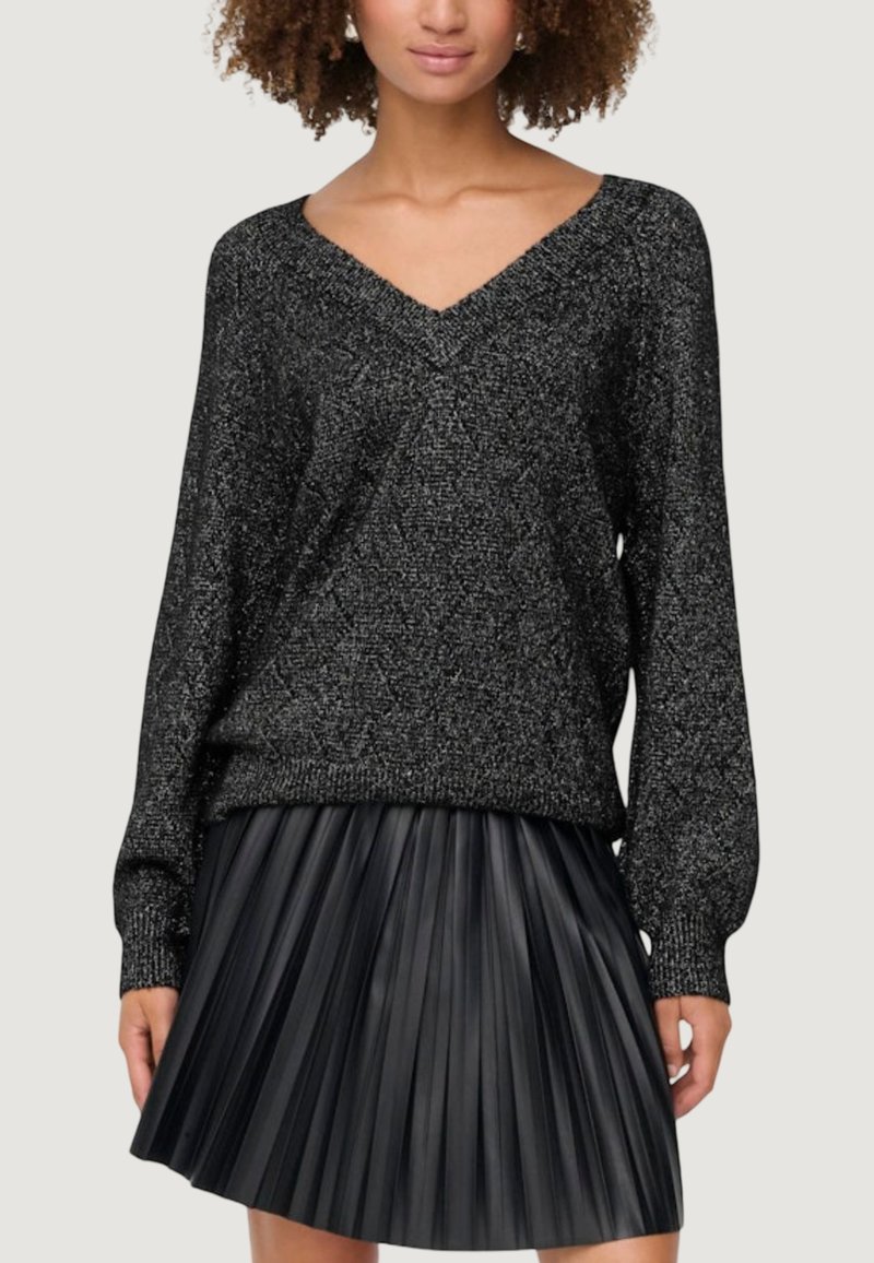 Maglione nero lavorato a maglia con scollatura a V, maniche lunghe e finitura testurizzata, abbinato a una gonna a pieghe nera in ecopelle.