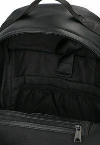 Interno di uno zaino nero con rivestimento in tessuto, compartimento con zip e tasca organizzativa. Texture liscia e materiali resistenti in tutto.