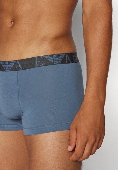 Bóxers de algodón azul con una cinturilla negra que presenta un patrón de logotipos azules. La tela es suave y tiene un ajuste ceñido en la cintura y los muslos.