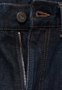 Mørkeblå denim jeans med en metalknap, lynlåsgylf og kontraststing. Synlig tekstur og lomme detaljer.