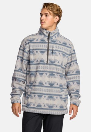 Sudadera de forro polar con cuello de media cremallera, con un patrón geométrico en azul y blanco. Textura suave, corte relajado y bolsillo frontal.