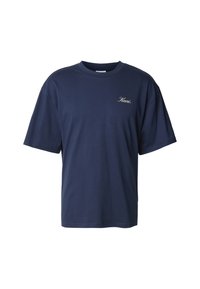 Tamsiai mėlynas medvilninis marškinėlis, turintis apvalų kaklą, trumpas rankoves, laisvą siluetą ir mažą siuvinėtą logotipą ant krūtinės.