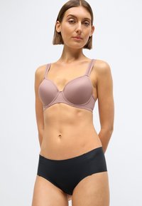 Purpurinės spalvos paminkštinta liemenėlė su reguliuojamomis petnešėlėmis, pasižyminti lygiu paviršiumi ir išlenktu dizainu. Derinama su juodais, vidutinio liemens aukščio kelnaitėmis.