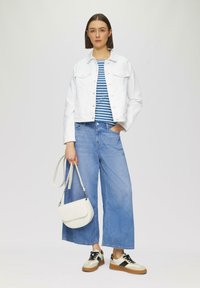 Chaqueta de mezclilla blanca, camisa a rayas azul y blanca, jeans de pierna ancha azul claro, bolsa de hombro blanca y zapatillas beis con acentos negros.