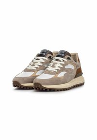 Zapatillas de ante beige y marrón con acentos en cuero blanco, cuello acolchado, cordones gruesos y suela de goma texturizada.