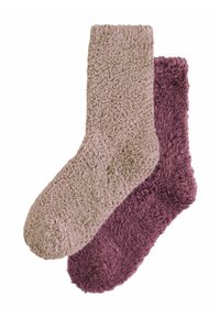 Ein Paar flauschige Socken: eine in hellem Beige und die andere in tiefem Burgunderrot. Beide besitzen eine weiche, strukturierte Oberfläche und runde Zehen.