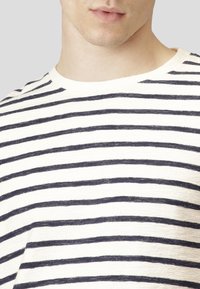 Camiseta de rayas con cuello redondo, con rayas marinas sobre un fondo crema, tela texturizada y un corte relajado.