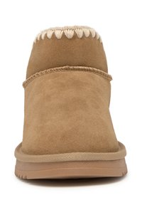 Botines de ante color canela con un interior suave forrado de piel, costuras texturizadas en la parte superior y suela plana de goma.