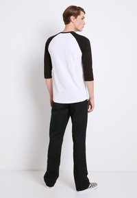 Herre 3/4 ærmet raglan t-shirt i hvid og sort, lavet af bomuld, med sorte ærmer, rund halsudskæring og afslappet pasform.