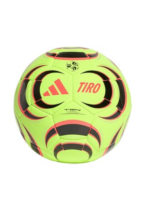 Fluorescencyjna żółta piłka nożna Adidas Tiro z czarnymi i czerwonymi wzorami geometrycznymi oraz logo Adidas na białym tle.