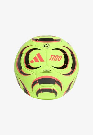 Fluorescencyjna żółta piłka nożna Adidas Tiro z czarnymi i czerwonymi wzorami geometrycznymi oraz logo Adidas na białym tle.