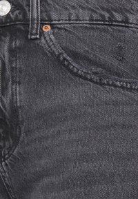 Mörkgrå denimjeans med en klassisk passform, lätt texturvariation och detaljer med kopparnitar vid fickan.