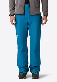 Niebieskie wodoodporne spodnie o prostym kroju nogawek, wykonane z trwałej tkaniny. Posiadają logo na udzie oraz regulowany pas.