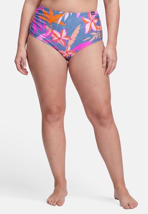 Vrouw draagt hoog getailleerde blauwe bikini met roze en oranje bloemenpatroon, staat blootsvoets tegen een witte achtergrond.