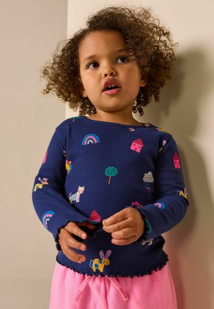 Laivastonsininen ribbineulottu pitkähihainen paita, jossa värikkäitä eläin- ja luontokuvioita ja aaltoileva helma. Yhdistetty pinkkeihin shortseihin.